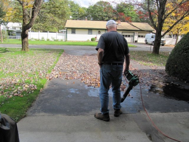 Person using an electric leaf blower to clear fallen leaves