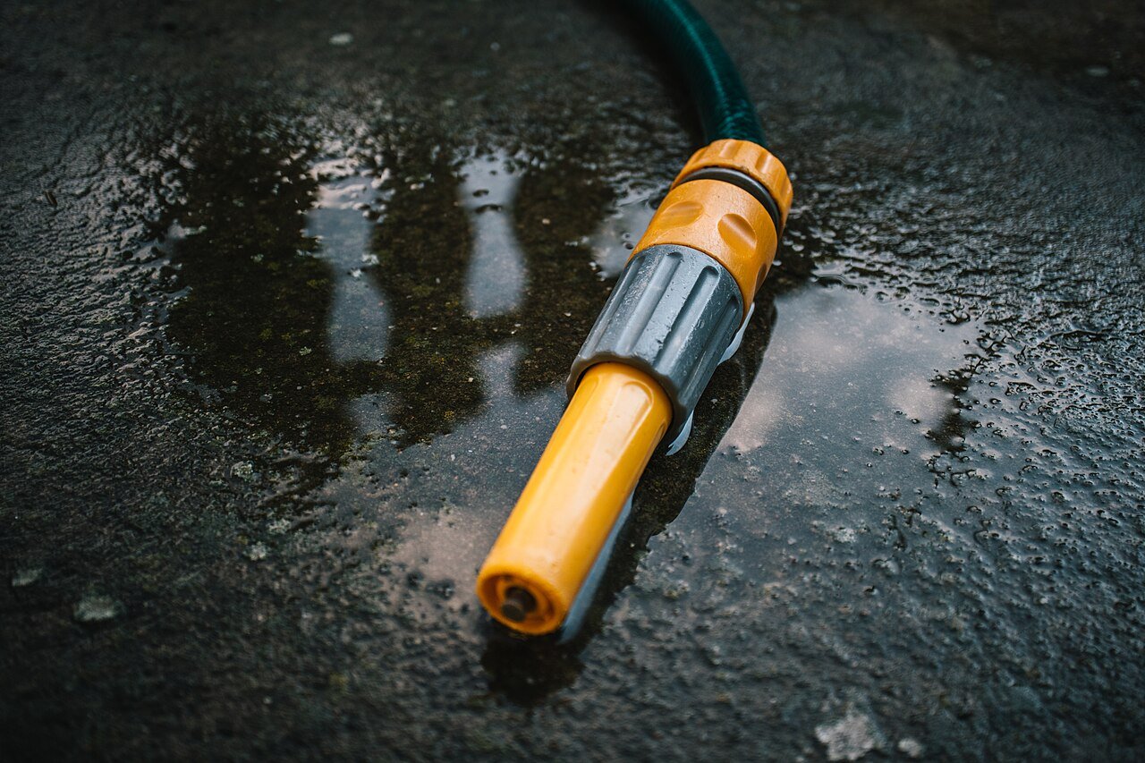 Garden hose nozzle on wet concrete after watering