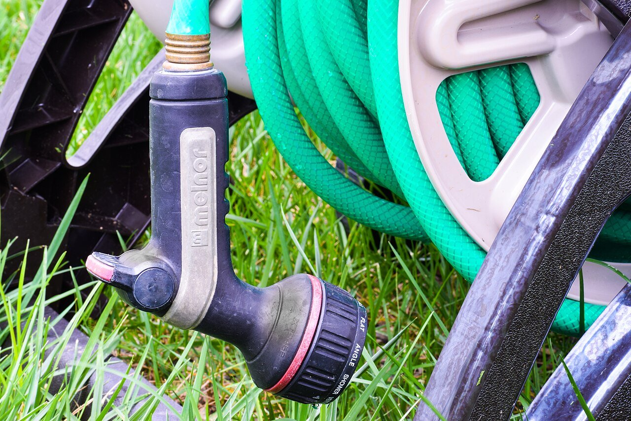Garden hose on a reel with a multi-pattern spray nozzle hanging from it