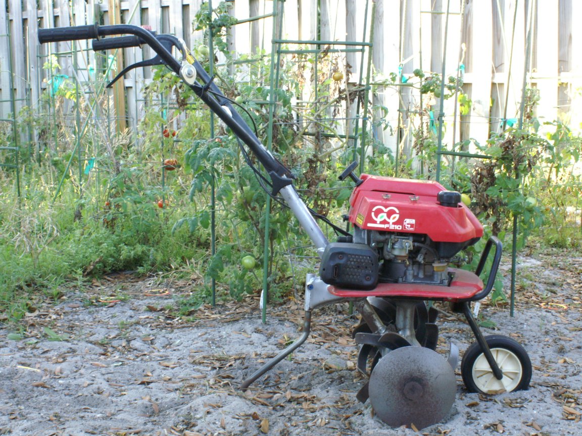 Honda F210 motorized garden tiller standing by tomato plants